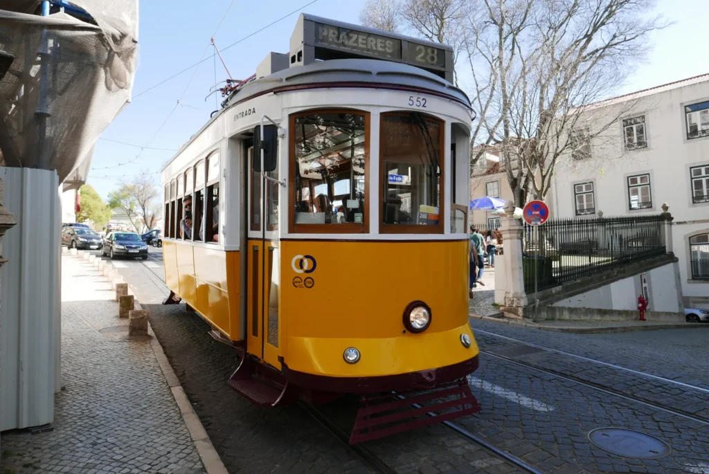 Yellow vintage tram 28 on a cobbled street in Lisbon, Portugal